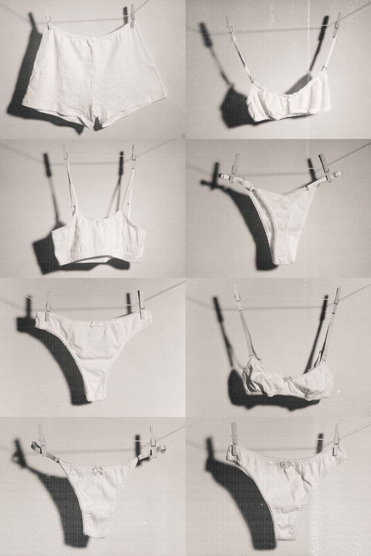 A grid of white cotton underwear and bralettes pegged to a washing line, photographed in soft black and white.