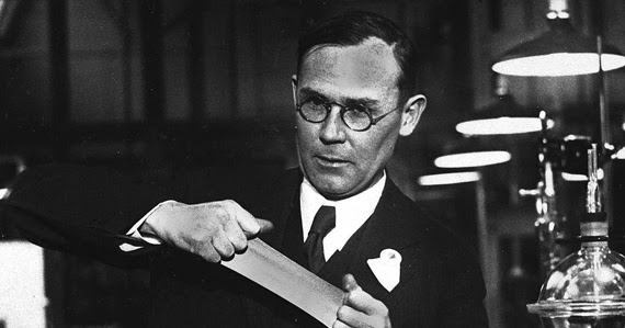A chemist in a 1930s laboratory stretching a length of synthetic filament between his hands